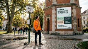 Ein Mann steht an der Straßenbahnhaltestelle in Graz und schaut sich die wechselnden Werbeanzeigen an.